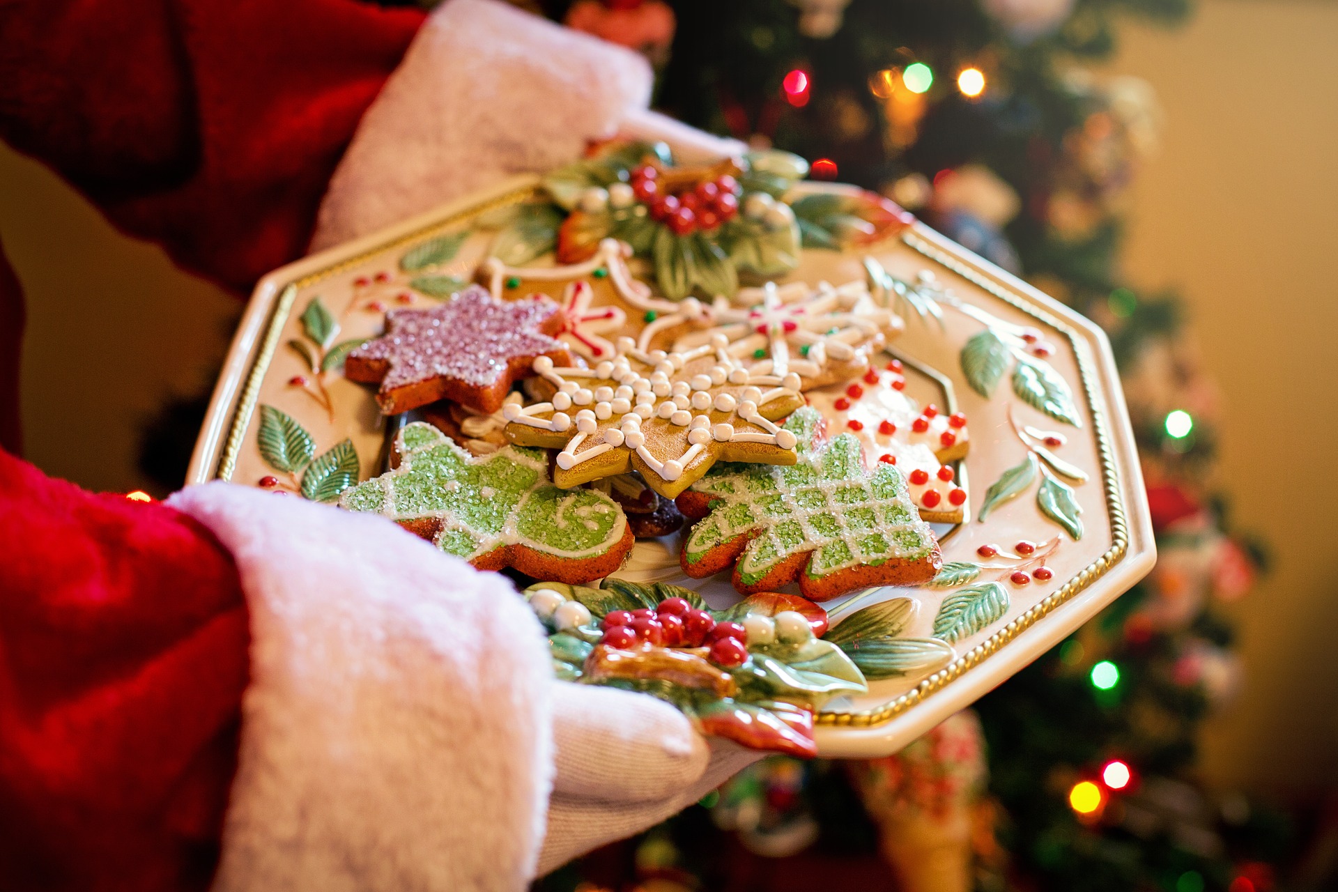 Santa holding a big plate of beautifully decorated Christmas cookiesis