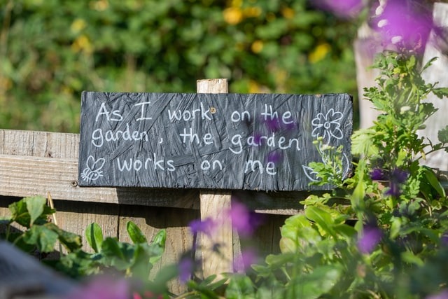 quote on a sign as I work on the garden the garden works on me