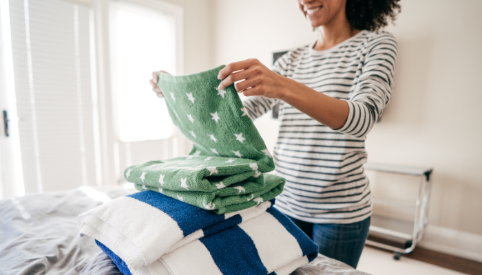 Mom folding beach towels on a bed.