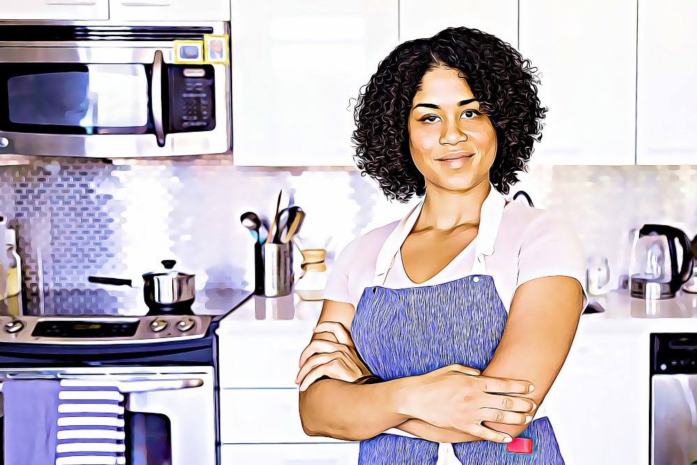 a smiling and healthy woman stands in front of a modern kitchen