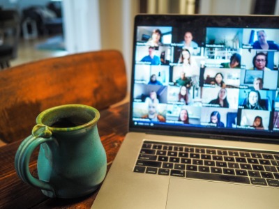 Picture of laptop showing online meeting next to green mug