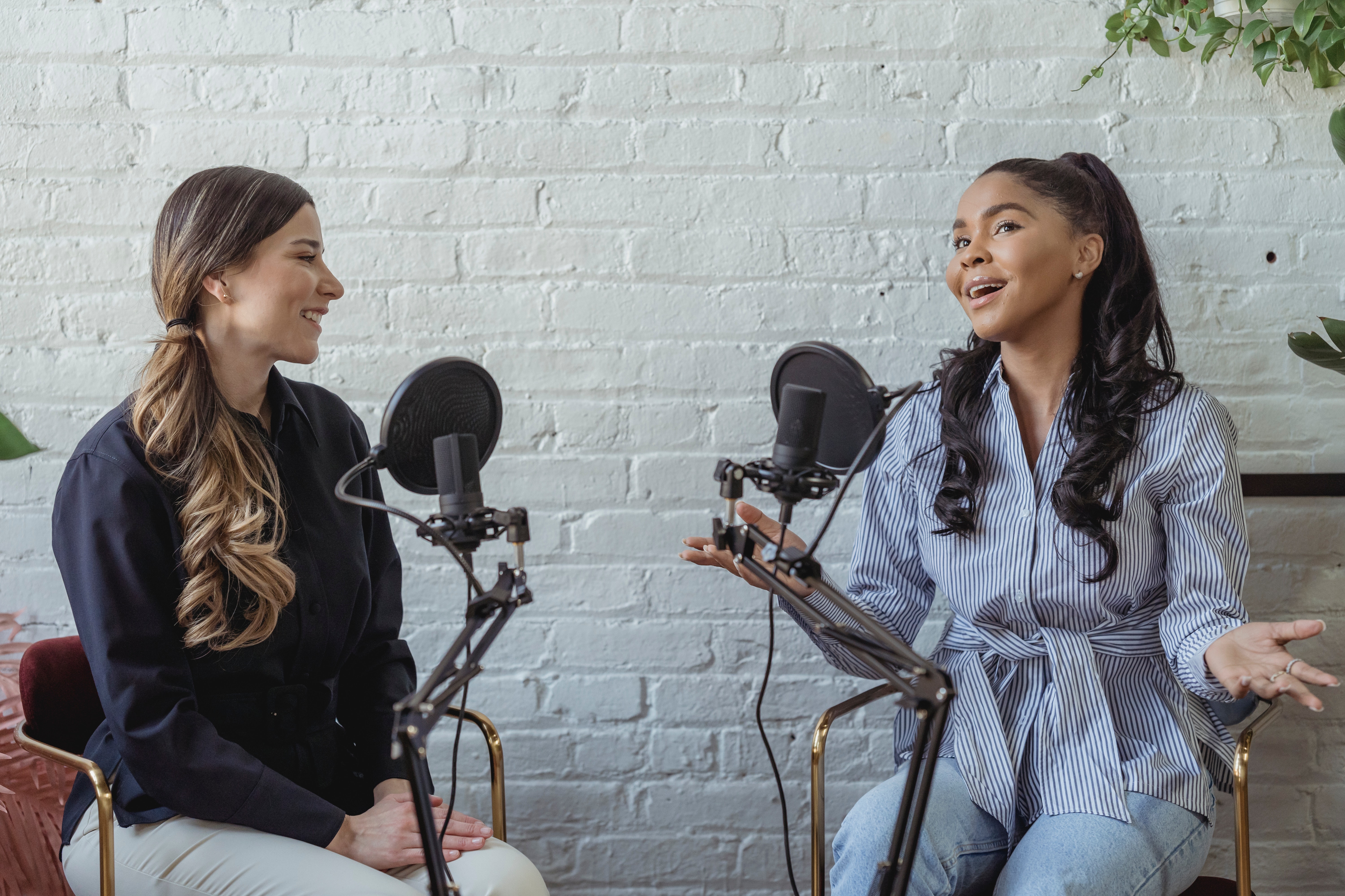Two women speaking into mics on a podcast