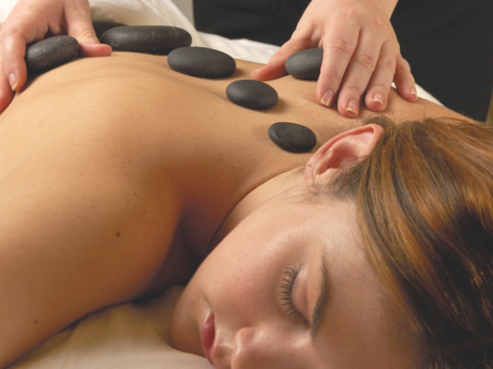 woman laying down with hot stones on her back