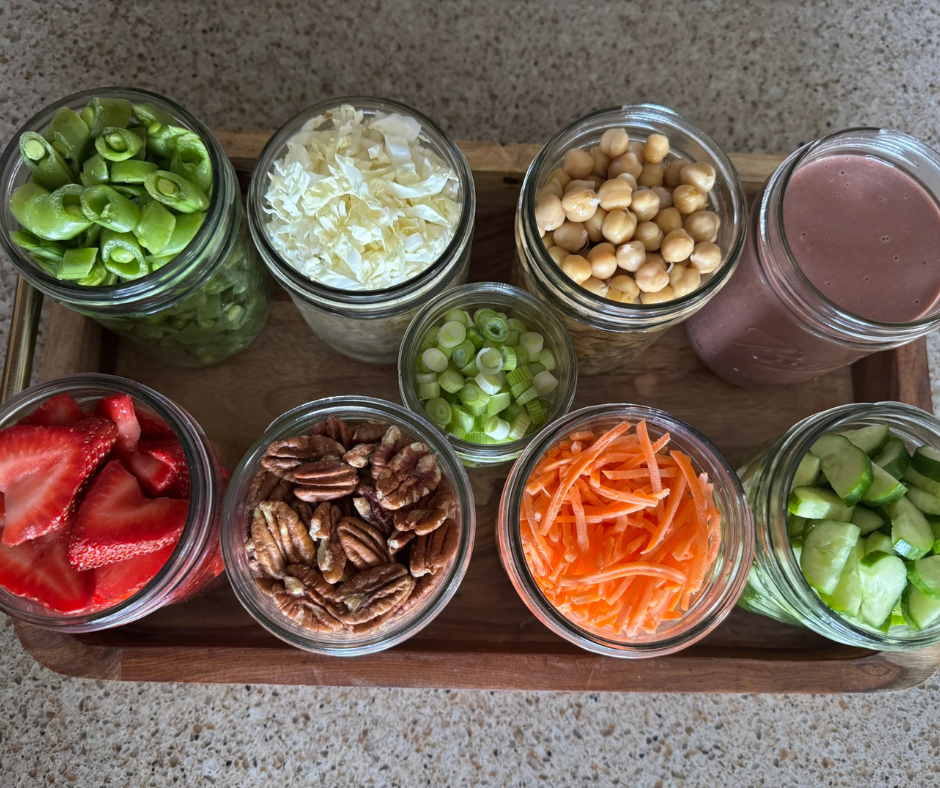 Prep jars filled with strawberries, chickpeas, cabbage, cucumber, snap peas, carrots, pecans, and scallions for the Strawberry Chickpea Garden Bowl.