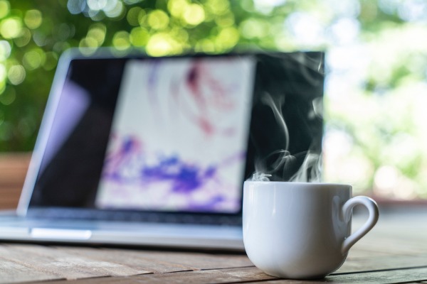 Laptop and coffee outdoors in sunshine. Free At 50 life as a blogger means working from anywhere and enjoying morning sun.