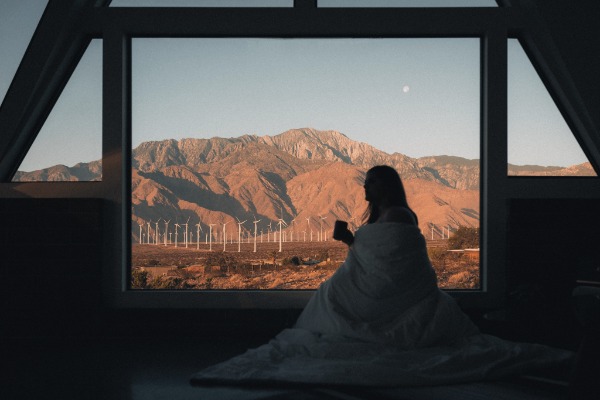 Woman looking out a window and drinking coffee. You can live your dream life by finding your passion and creating a business from it.