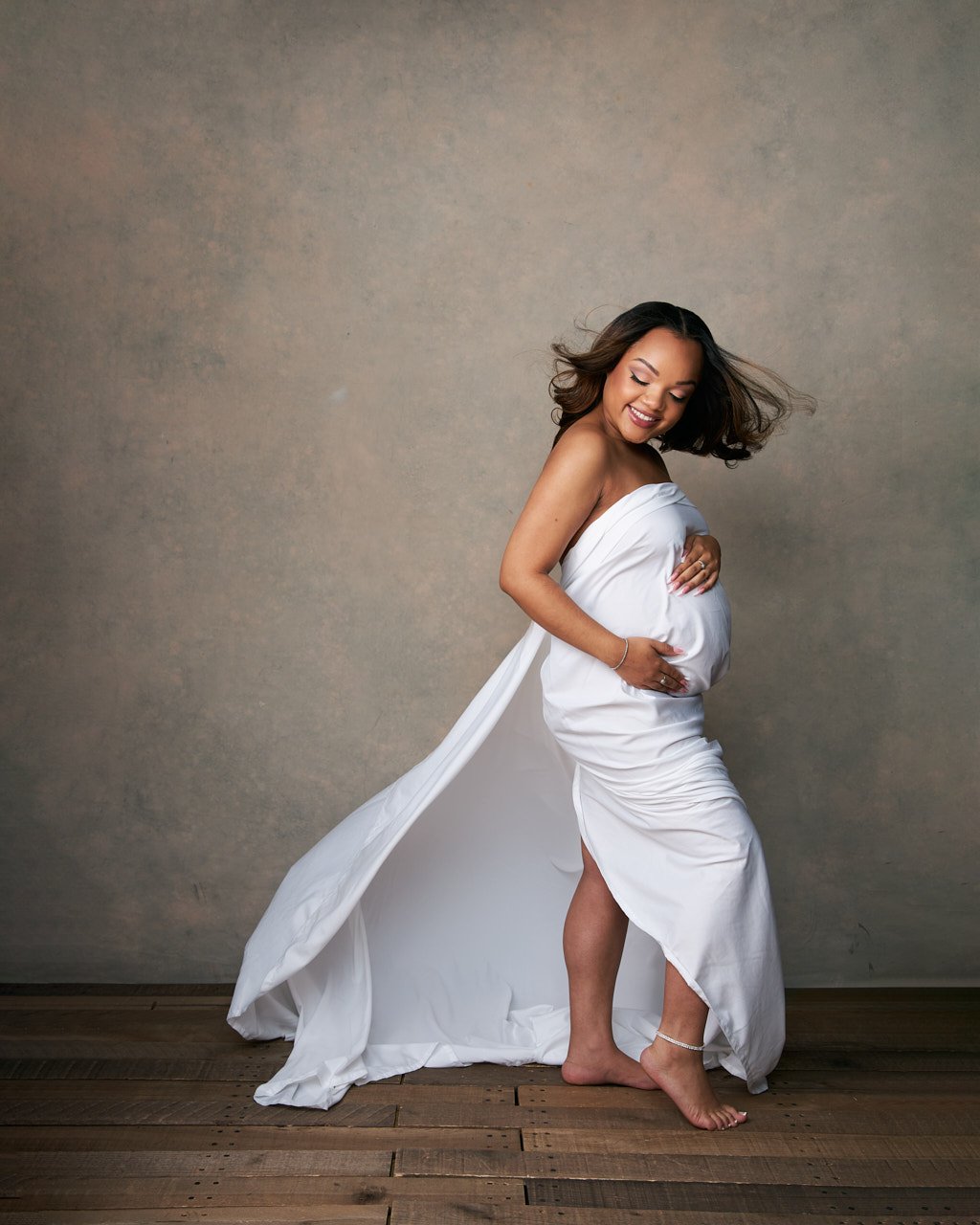 Pregnant woman of color in flowing white fabric maternity outfit. Maternity portrait photographer near Washington DC  Portraits by Jared Wolfe in Alexandria VA