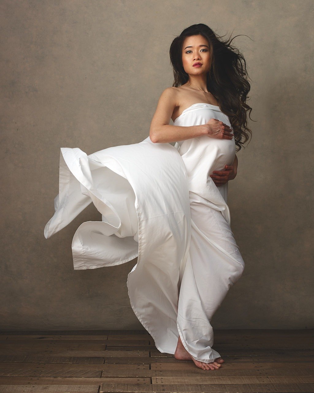 Maternity photo of pregnant asian woman in white flowing fabric. Maternity photographer near Washington DC. Portraits by Jared Wolfe in Alexandria VA