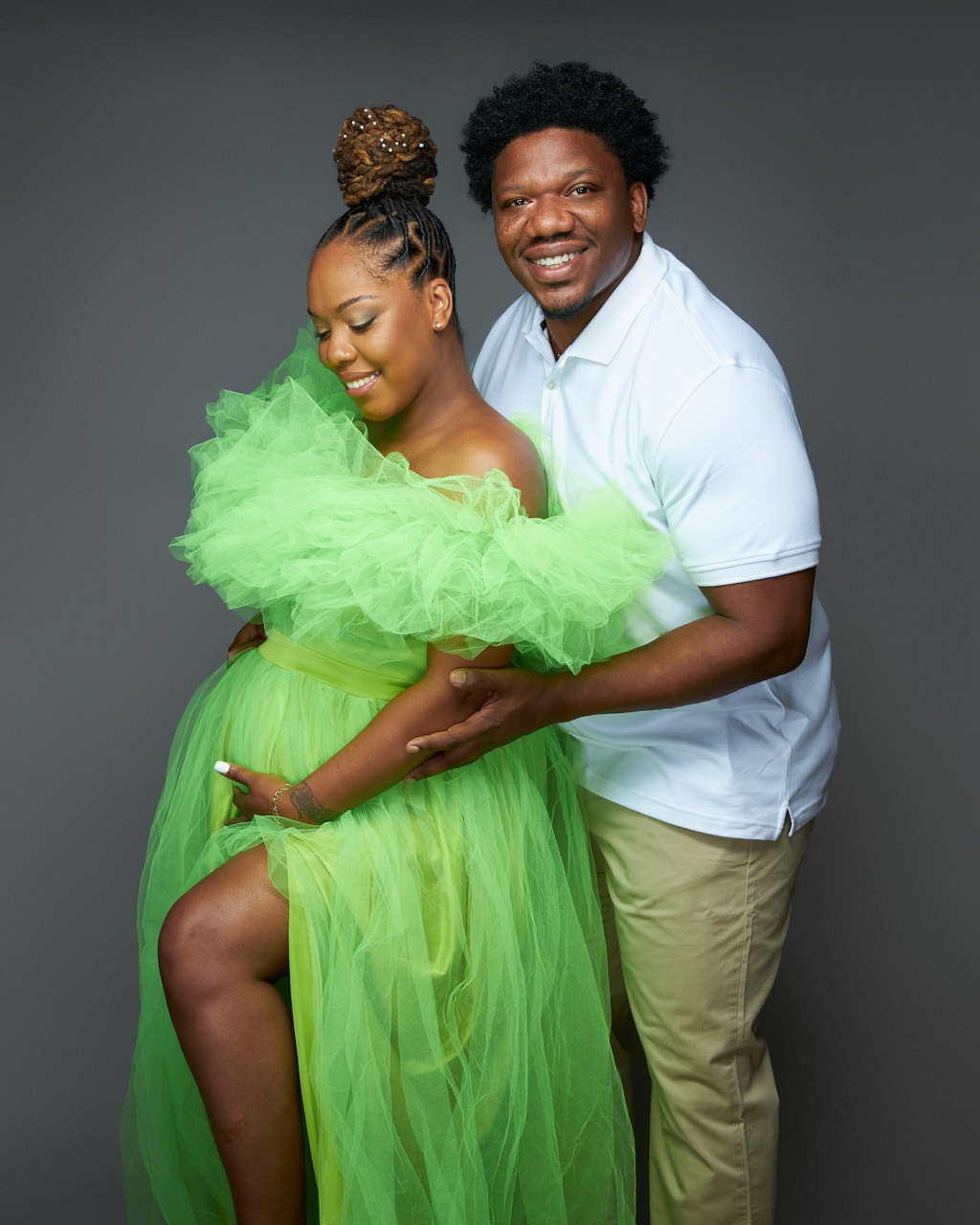 Pregnant woman of color in bright green materbity dress with husband. Maternity portrait photographer near Washington DC  Portraits by Jared Wolfe in Alexandria VA