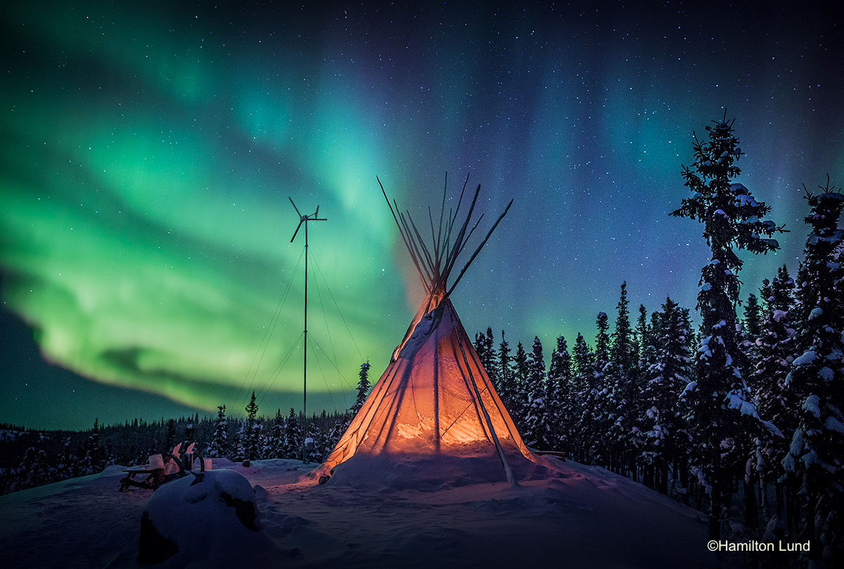 Emerald freeways dance above a tipi fire at Blachford Lake Lodge in Canada’s North West Territories. By Hamilton Lund.